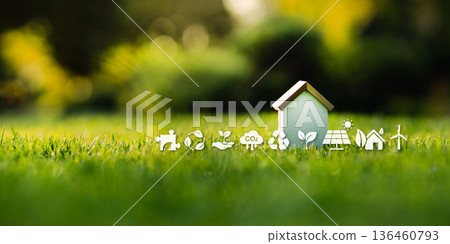 Eco-friendly house model on green grass with sustainability icons. 136460793