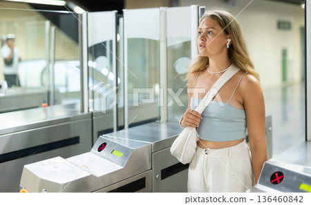 Young woman passes through turnstile in subway Young woman passes through turnstile in subway 136460842