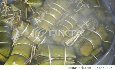 Sticky rice with coconut and banana filling, wrapped in banana leaves, cooked and steamed. Sticky rice with coconut and banana filling, wrapped in banana leaves, cooked and steamed. 136460896