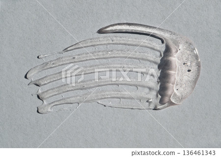 Transparent skincare product swatched creating streak on light surface 136461343