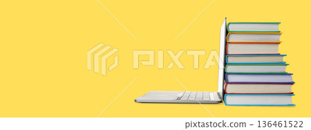 A laptop beside colorful books on a bright background 136461522