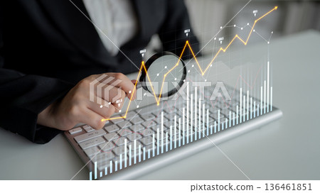 Business professional analyzing financial data trends with magnifying glass over keyboard and digital graphical representation of growth metrics Scalp Business professional analyzing financial data trends with magnifying glass over keyboard and digital graphical representation of growth metrics Scalp 136461851