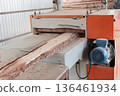 The edge of the board is cut on the machine. Sawing wood. Wood processing workshop. The woodworking industry. 136461934