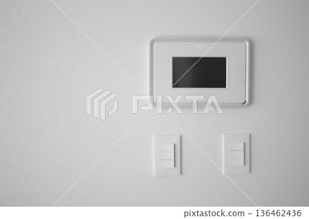 It's a white wall with an intercom and a switch. It's a white wall with an intercom and a switch. 136462436