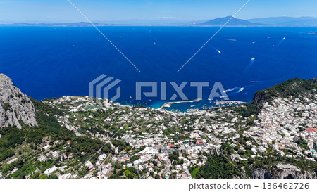 Breathtaking view over the azure waters and charming coastal town of Capri amidst clear blue skies and distant mountains 136462726