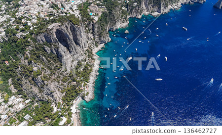 Vibrant boats dot the turquoise waters of the stunning coastline in Capri under a bright summer sky Vibrant boats dot the turquoise waters of the stunning coastline in Capri under a bright summer sky 136462727