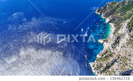 Vibrant coastal landscape with tranquil waters and boats near rocky shoreline under clear skies Vibrant coastal landscape with tranquil waters and boats near rocky shoreline under clear skies 136462728