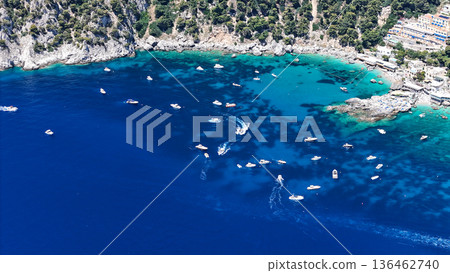 Breathtaking aerial view of boat-filled turquoise waters off a coastal town during summer on a sunny day 136462740