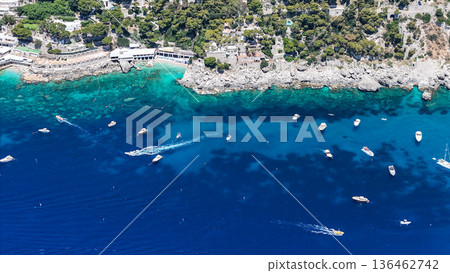 Crystal clear waters entice boats in a serene coastal bay surrounded by lush greenery and picturesque cliffs 136462742
