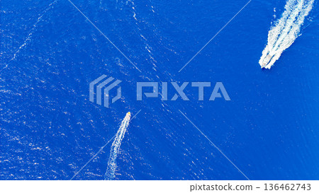 Vibrant blue waters highlight the sleek speedboats racing across the ocean under the bright sun 136462743