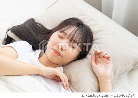 A young woman sleeping in bed 136462754