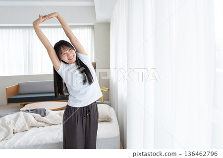 A woman who gets up in the morning and stretches 136462796