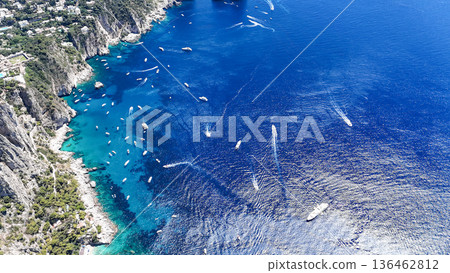 Vibrant blue waters of Capri invite exploration by boats under the sun in a stunning coastal landscape 136462812