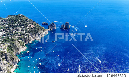 Breathtaking azure waters surround the stunning Faraglioni rocks in Capri during a vibrant summer day filled with boats Breathtaking azure waters surround the stunning Faraglioni rocks in Capri during a vibrant summer day filled with boats 136462813
