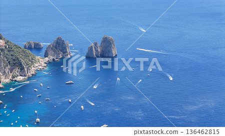 Lush coastal panorama featuring dazzling blue waters and boats near dramatic rocky formations in Mediterranean paradise 136462815