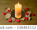Burning white candle on mirror surrounded by red hearts and dry leaves. 136463112
