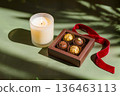 Box of chocolate truffles with burning candle and red velvet ribbon. 136463113