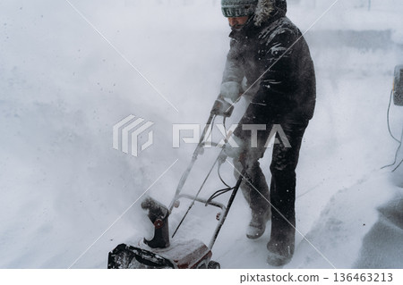 man clearing snowin countryside using electric snow blower man clearing snowin countryside using electric snow blower 136463213