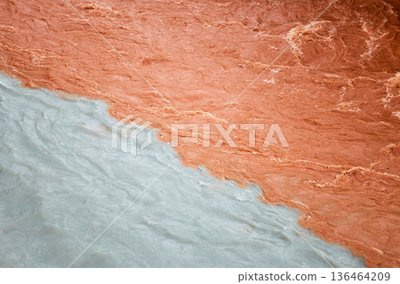 Confluence of two rivers with distinct colors. Brown muddy water meeting light blue glacier water. Natural phenomena background. Confluence of two rivers with distinct colors. Brown muddy water meeting light blue glacier water. Natural phenomena background. 136464209