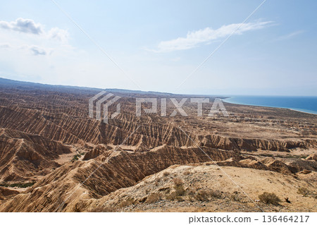 Aksai Canyon panorama with vast eroded landscape near calm water. Natural geological formation in Kyrgyzstan for nature tourism. 136464217
