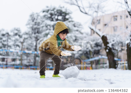 一個6歲男孩在雪地公園玩耍 136464382