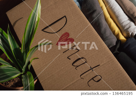 Many clothing items are organised in a donation box with a message promoting kindness and community support Many clothing items are organised in a donation box with a message promoting kindness and community support 136465195