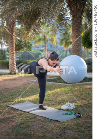 Woman Doing Balance Exercise With Stability Ball In Park For Outdoor Fitness And Flexibility Woman Doing Balance Exercise With Stability Ball In Park For Outdoor Fitness And Flexibility 136465450