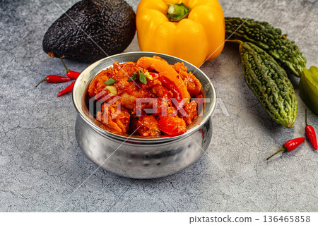 Spicy chicken curry in a bowl surrounded by fresh bell pepper, avocado, and bitter melon Spicy chicken curry in a bowl surrounded by fresh bell pepper, avocado, and bitter melon 136465858