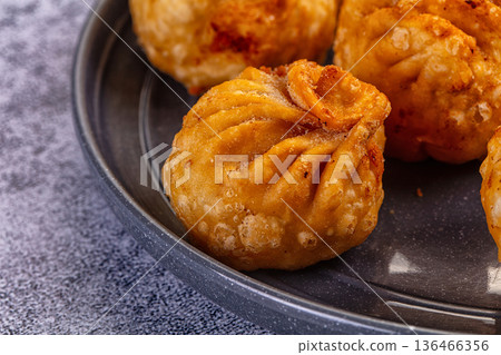 Golden fried dumplings momo in a skillet with fresh vegetables and flatbread Golden fried dumplings momo in a skillet with fresh vegetables and flatbread 136466356