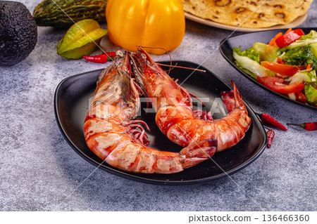Grilled giant red prawns in a pan with fresh avocado, bell pepper, and salad on a stone table Grilled giant red prawns in a pan with fresh avocado, bell pepper, and salad on a stone table 136466360
