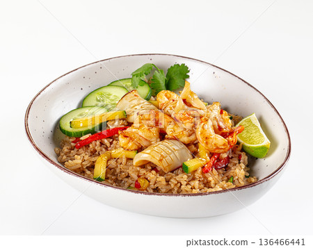 Asian fried rice with shrimp, calamari, and fresh vegetables in a bowl isolated on white. Asian fried rice with shrimp, calamari, and fresh vegetables in a bowl isolated on white. 136466441
