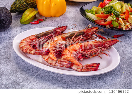 Grilled giant red prawns in a pan with fresh avocado, bell pepper, and salad on a stone table 136466532