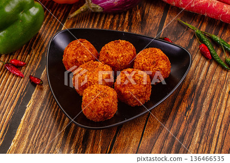 Golden fried cheese and vegetable balls, appetizer dish with fresh chili, peppers, and carrots on a wood table. 136466535