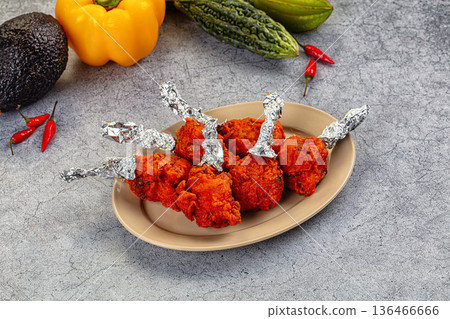 Spicy Indian Chicken Lollipops appetizer in a bowl with fresh vegetables 136466666