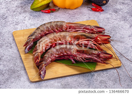 Fresh raw giant red prawns on a plate with chili peppers and tropical vegetables. Fresh raw giant red prawns on a plate with chili peppers and tropical vegetables. 136466670