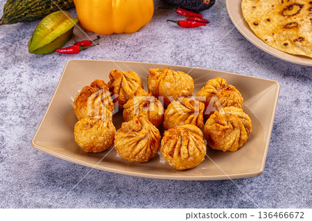 Golden fried dumplings momo in a skillet with fresh vegetables and flatbread Golden fried dumplings momo in a skillet with fresh vegetables and flatbread 136466672