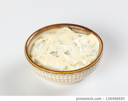 Creamy tartar sauce with herbs and pickles in a patterned ceramic bowl isolated on white 136466685
