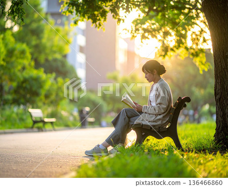 Fresh green season, urban buildings, woman reading in park 136466860