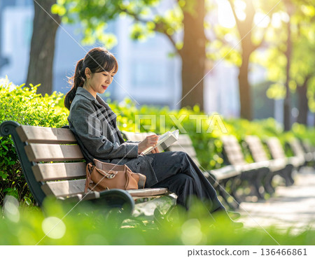 Fresh green season, urban buildings, woman reading in park 136466861