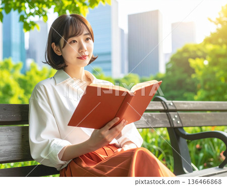 Fresh green season, urban buildings, woman reading in park 136466868