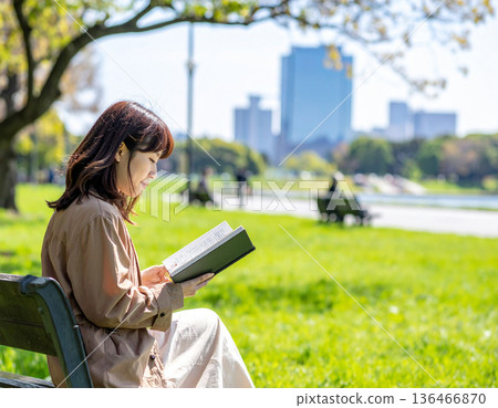 Fresh green season, urban buildings, woman reading in park 136466870
