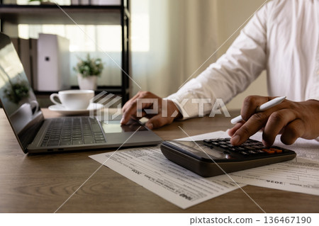 Accountant with US tax forms Accountant uses calculator tax papers falling review tax forms and financial documents, business accounting, tax filing preparation 136467190