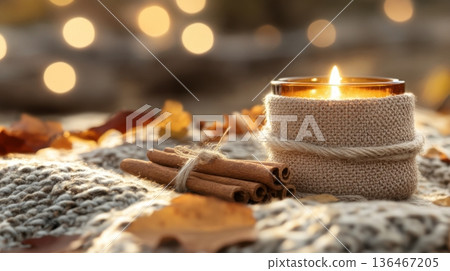 Fabric-wrapped podium beside tea light candle and cinnamon sticks on soft blanket with maroon leaves 136467205