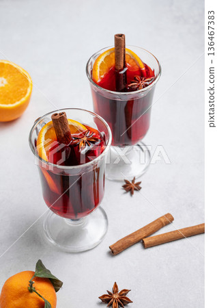 Two glasses of mulled wine, orange, cinnamon, and star anise on a light background Two glasses of mulled wine, orange, cinnamon, and star anise on a light background 136467383
