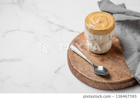 Dalgona coffee. Whipped instant iced coffee in a glass on a wooden board on a marble background 136467393