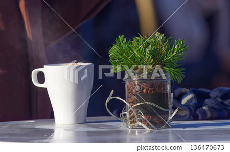 Cozy Outdoor Coffee Moment With White Mug, Coffee Beans, Pine Branch Jar, Steam, And Lights 136470673
