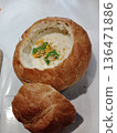Creamy soup served in hollowed bread bowl with garnishes. 136471886