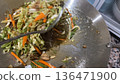 Spoon lifting mixed vegetables from wok during cooking. 136471900
