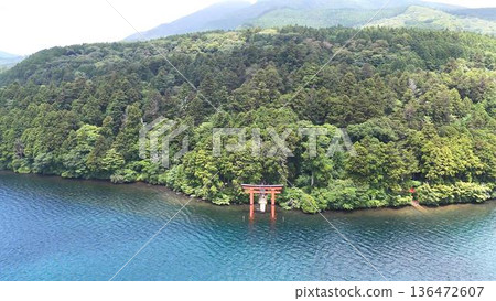 The beautiful contrast between the green of Hakone Shrine's forest and the blue of Lake Ashi creates a peaceful torii gate | A sacred landscape by the quiet lakeside 136472607