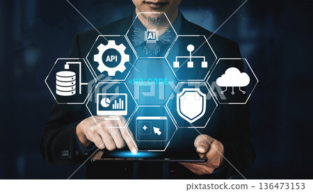 Man in Suit Using Tablet with Digital Icons Representing Technology, Data, and Innovation in Modern Business Environment for Stock Image Quark 136473153